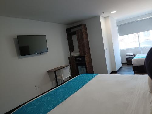 um quarto de hotel com uma cama e uma televisão de ecrã plano em HOTEL AMERICAN VISA CORPORATE em Bogotá