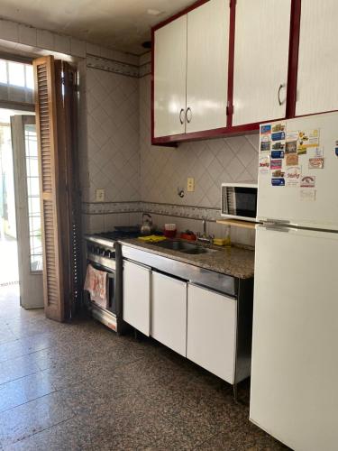 cocina con armarios blancos y nevera en Casa en el Gran Mendoza en Mendoza