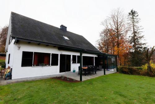 a white house with a black roof and a yard at La colline aux hirondelles in La Roche-en-Ardenne