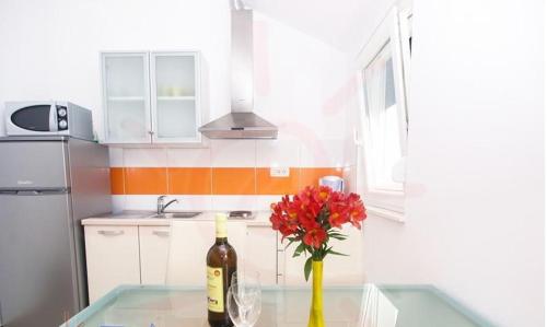 una cocina con una botella de vino y un jarrón con flores rojas en Stari Dvori, en Trogir