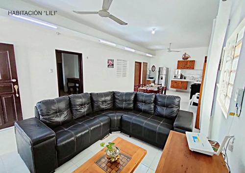 a living room with a black leather couch and a table at Departamentos Ileana in Cozumel