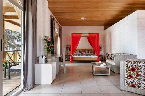 a living room with a bed with a red curtain at Hotel Coucoue Lodge in Assinie