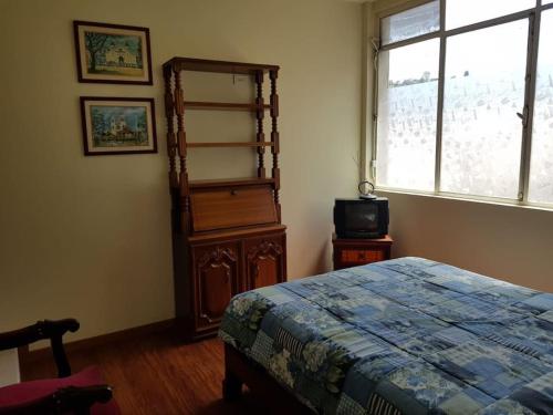 a bedroom with a bed and a tv and a window at Beautiful & fully renovated flat in historic city center in Quito