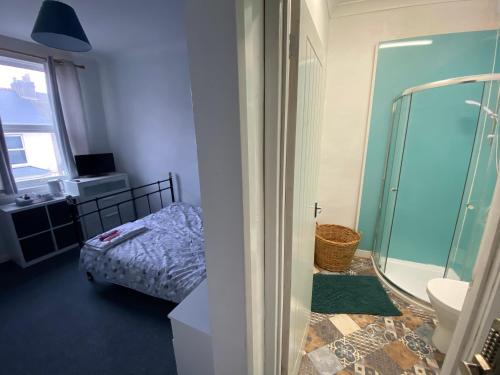 a bathroom with a shower and a bed in it at The Nook En-suite Room in Plymouth