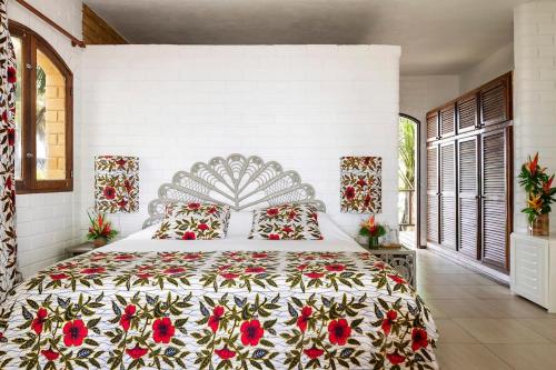 a bedroom with a large bed with a floral bedspread at Hotel Coucoue Lodge in Assinie