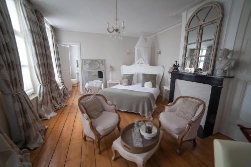 a bedroom with a bed and two chairs and a table at Bienvenue Chez Nous in Bergues