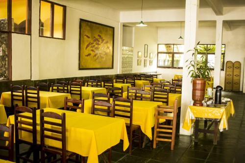 a dining room with yellow tables and chairs at Pousada do Preto in Praia do Bananal