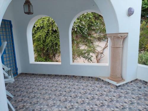 two arched windows in a white wall with a column at Magnifique villa en Centre Ville in Monastir
