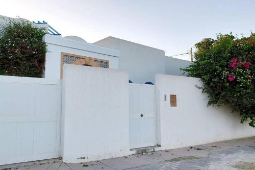 a white fence with two white doors and flowers at Magnifique villa en Centre Ville in Monastir
