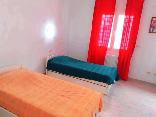 a room with two beds and red curtains at Magnifique villa en Centre Ville in Monastir