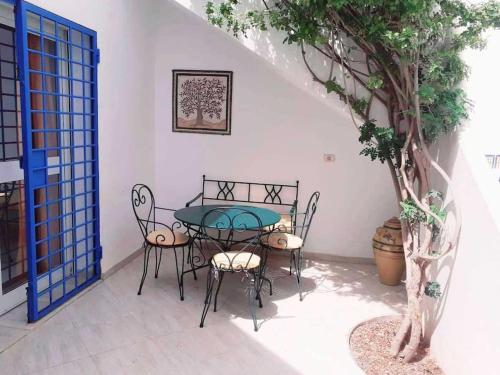 un patio con mesa, sillas y un árbol en Magnifique villa en Centre Ville, en Monastir