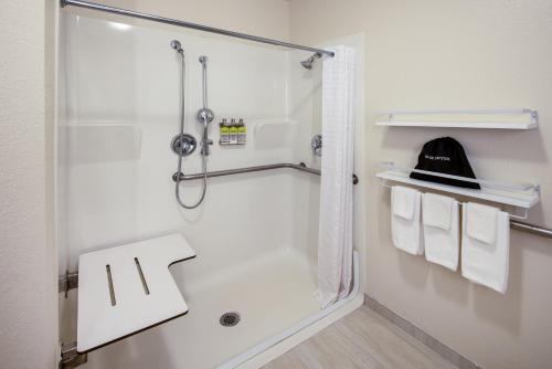 a white bathroom with a shower and towels at Candlewood Suites Manassas, an IHG Hotel in Manassas