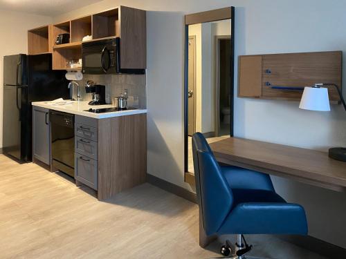 a kitchen with a desk and a blue chair at Candlewood Suites Manassas by IHG in Manassas