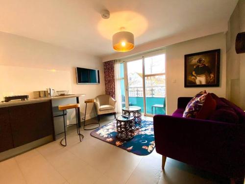 a living room with a couch and a table and a kitchen at Stunning Apartment - 1 Minute walk to Poole Quay - Great Location - Free Parking - Fast WiFi - Smart TV - Newly decorated - sleeps up to 2! Close to Poole & Bournemouth & Sandbanks in Poole