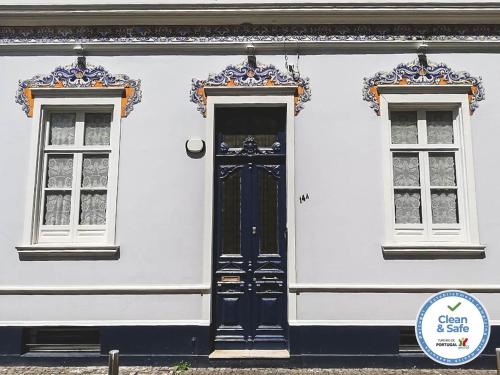 ein weißes Gebäude mit einer blauen Tür und zwei Fenstern in der Unterkunft Casa do Vereador in Ponta Delgada