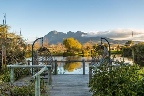 a wooden bridge over a river with two chairs at Santé Wellness Retreat & Spa in Paarl