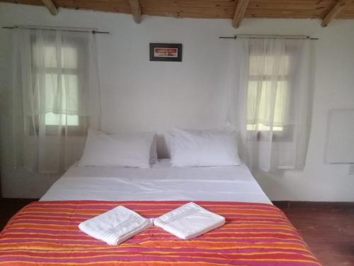 un letto con due asciugamani bianchi sopra di Cabañas Lagos Dos Molinos a Marcos Paz