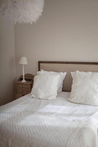 a bed with white sheets and pillows on it at Bienvenue Chez Nous in Bergues