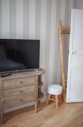 a television sitting on top of a wooden dresser with a stool at Bienvenue Chez Nous in Bergues