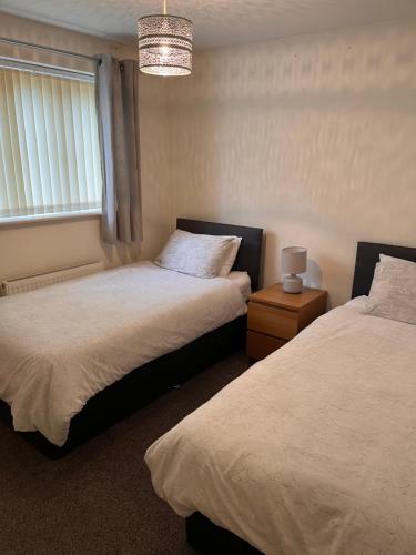 a bedroom with two beds and a chandelier at At home in the city serviced apartments Newport in Newport