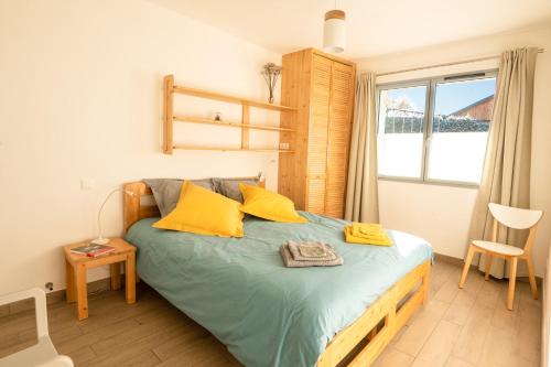 a bedroom with a bed with yellow pillows and a window at Gite Le Rucher in Lans-en-Vercors