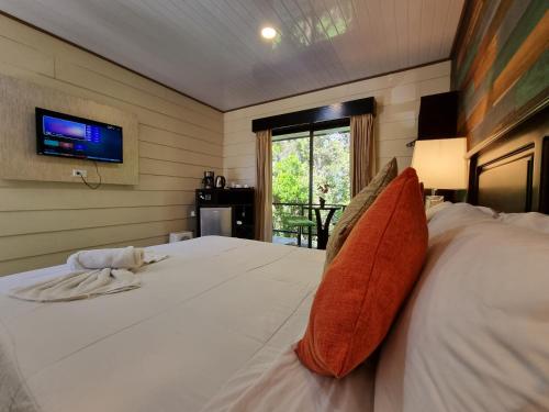 Schlafzimmer mit einem weißen Bett und einem TV an der Wand in der Unterkunft Calathea Lodge Monteverde in Monteverde Costa Rica