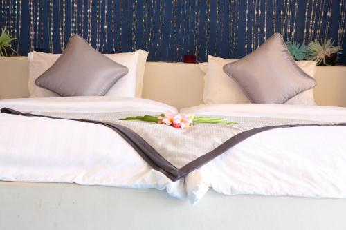 two beds with white pillows with a flower on them at Vacation Village Phra Nang Lanta - SHA Extra Plus in Ko Lanta