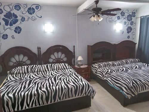 2 camas en un dormitorio con estampado de cebra en El Hogar de Carmelita, en Guanajuato