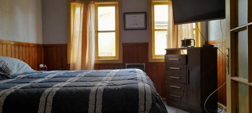 1 dormitorio con 1 cama y vestidor con TV en Pensión al sur del.mundo, en Punta Arenas