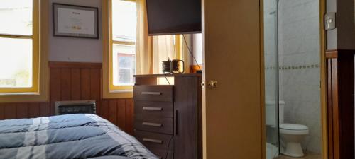 a bedroom with a bed and a dresser and a bathroom at Pensión al sur del.mundo in Punta Arenas