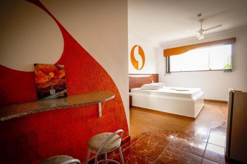 een kamer met een bed en een rode muur bij Motel Ipe in Araçariguama