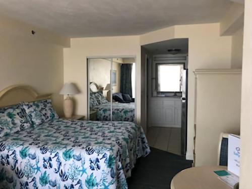 um quarto de hotel com uma cama e um espelho em Beachin Oceanfront Studio em Daytona Beach
