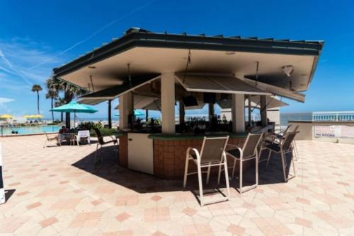 um bar na praia com cadeiras e guarda-sóis em Beachin Oceanfront Studio em Daytona Beach