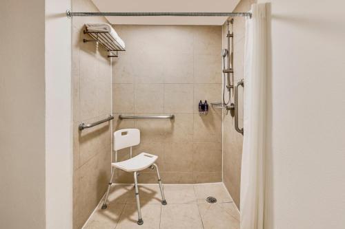 a shower with a white chair in a bathroom at Fiesta Inn Guadalajara Expo in Guadalajara
