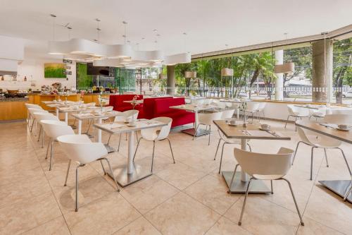 a restaurant with white tables and white chairs at Fiesta Inn Guadalajara Expo in Guadalajara