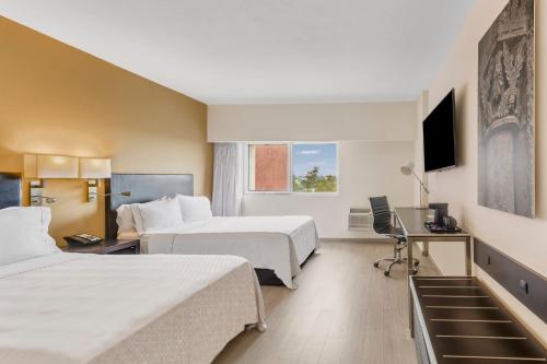 a hotel room with two beds and a desk at Fiesta Inn Guadalajara Expo in Guadalajara
