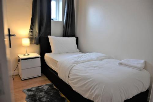niewielka sypialnia z białym łóżkiem i lampką w obiekcie London 4 Bedroom House w Londynie