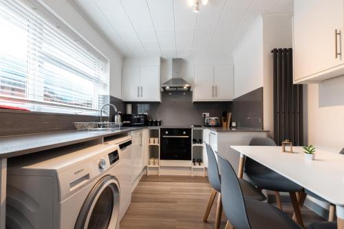 a kitchen with a washing machine and a table at Woodley house in Reading