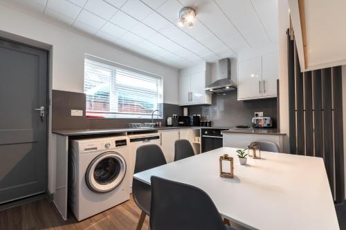 a kitchen with a washing machine and a table with chairs at Woodley house in Reading