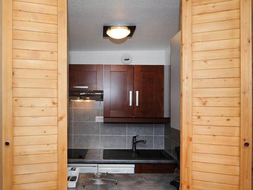 a kitchen with a sink and wooden cabinets at Appartement Les Menuires, 2 pièces, 5 personnes - FR-1-344-856 in Les Menuires