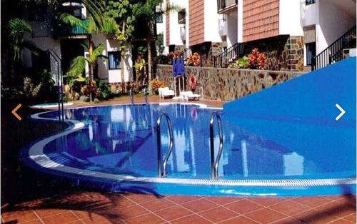 a blue swimming pool in front of a building at Casa Alisios in Playa de Santiago