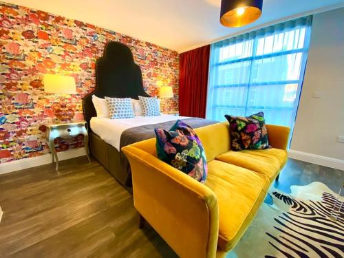 a bedroom with a bed and a yellow couch at Luxurious Studio Apartment - 1 Minute walk to Poole Quay - Great Location - Free Parking - Fast WiFi - Smart TV - Newly decorated - sleeps up to 2! Close to Poole & Bournemouth & Sandbanks in Poole