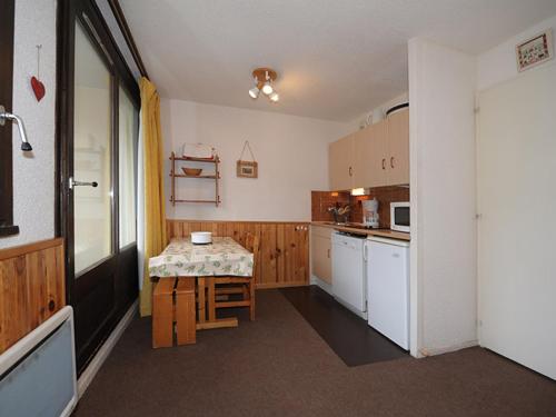 une cuisine avec une table et une petite table. dans l'établissement Studio cosy proche des pistes, 4 pers, balcon, WiFi gratuit, cuisine équipée - FR-1-344-1069, aux Menuires