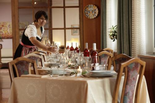 a woman standing in front of a table with wine glasses at Hotel Lido - slow & natural living in Molveno
