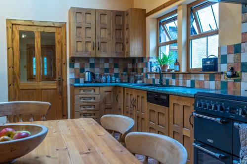 una cocina con armarios de madera y una mesa con un bol de fruta en Ferroch the place with an amazing view!, en Torridon