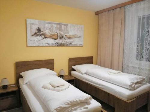 two twin beds in a room with a window at Apartmán West in Poprad