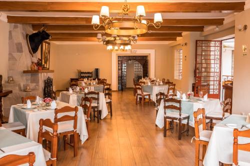 a restaurant with white tables and chairs and a chandelier at HOTEL & SPA LAGUNA SECA in Los Baños del Inca