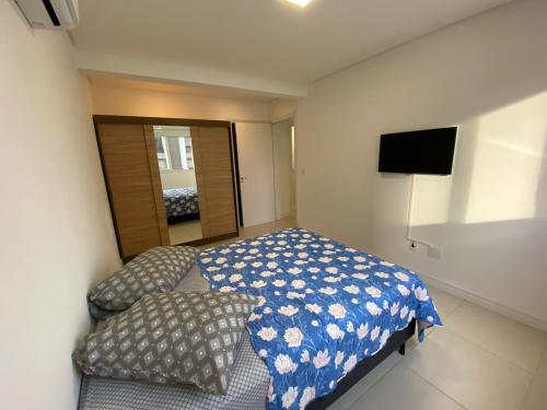 a small bedroom with a bed and a mirror at Praia Grande (12) - 3 quartos - 1 quadra Mar in Torres