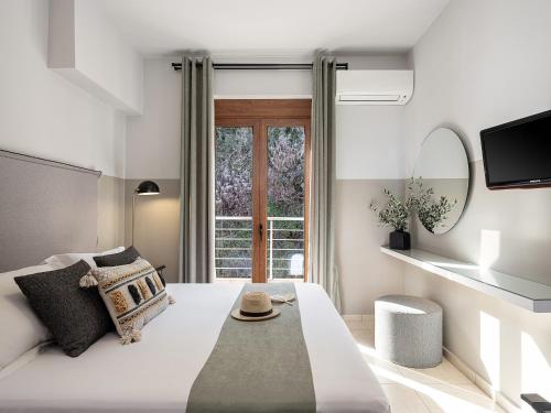 a bedroom with a large white bed with a window at Porto Kalyves Seaside Aparthotel in Kalyves