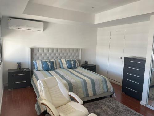 ein Schlafzimmer mit einem Bett, einem Stuhl und einer Kommode in der Unterkunft 2 Bedrooms 2 Bathrooms Beach Front Apt @ Coral in San Juan